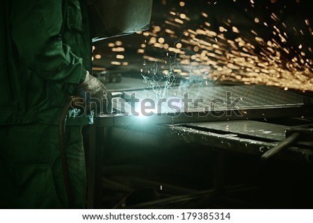 Industrial worker cutting and welding metal with many sharp sparks