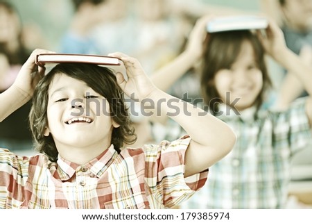 Group of kids at school room having fun time holding books on heads