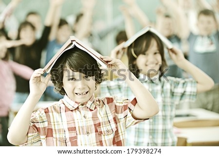 Group of kids at school room having fun time holding books on heads