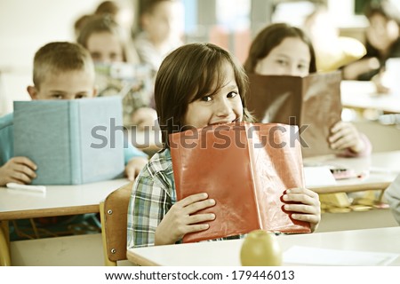 Cheerful kids at school room having education activity with books