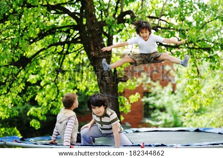 Cheerful kids having fun jumping on trampoline
