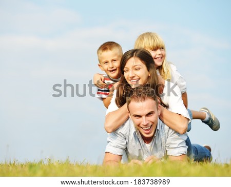 Young family lying on green summer grass meadow having happy life