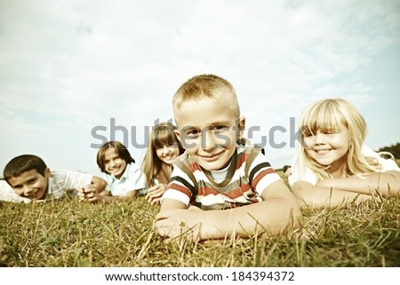 Colorized image of a happy boys and girls sitting on summer grass meadow