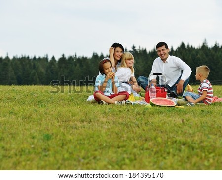 Family with children having picnic on meadow near forest trees