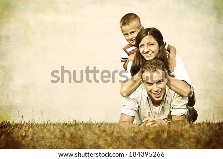 Vintage filtered image of a family lying on green summer grass meadow having happy life