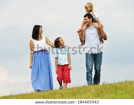 Happy young family of four members on green summer grass meadow having fun