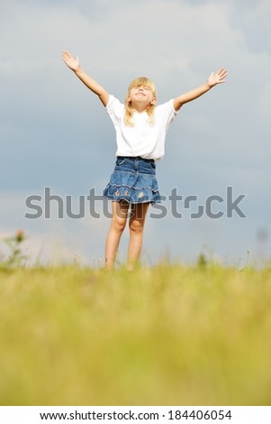 Happy little blonde girl on summer grass meadow in nature having happy time