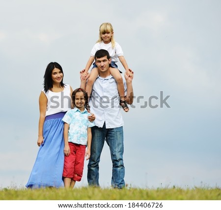 Happy young family of four members on green summer grass meadow having fun