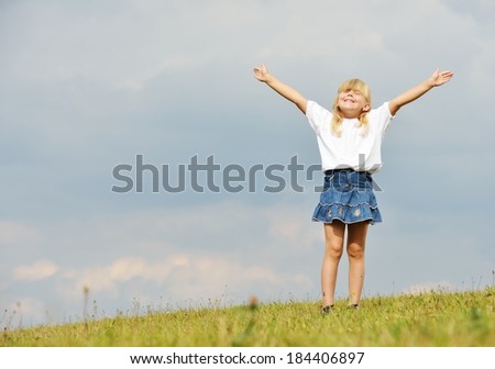 Happy little blonde girl on summer grass meadow in nature having happy time
