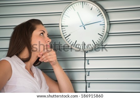 Bored executive woman looking at a clock on the wall