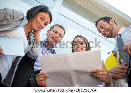 Happy executive people reviewing documents in front of modern building