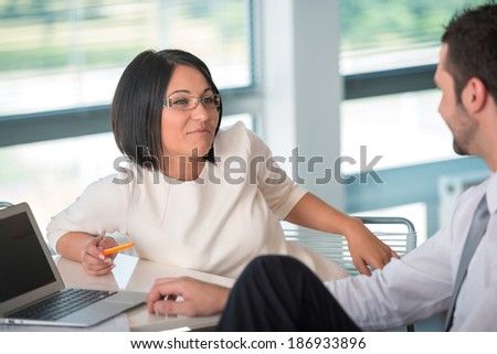 Smiling business woman flirting with male colleague in corporate environment