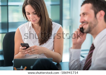 Business woman typing with cellphone in modern office