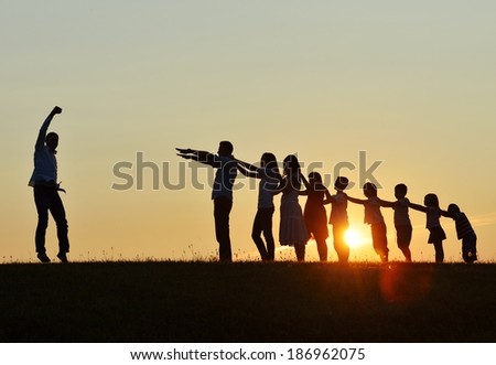 People silhouettes on summer sunset meadow making progress to success