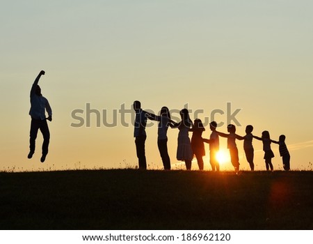 People silhouettes on summer sunset meadow making progress to success