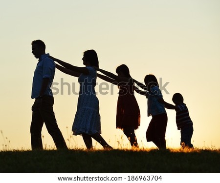 Happy family silhouettes on summer meadow