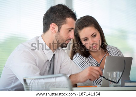 Busy couple of managers working with laptop in office