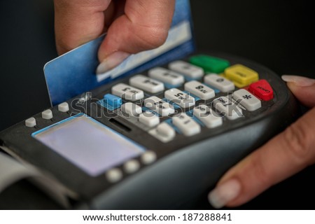 Hands swiping magnetic card on pos terminal