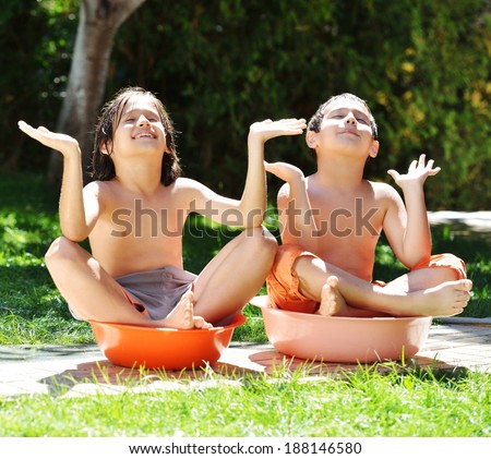 Happy kids playing and splashing with water sprinkler on summer grass yard