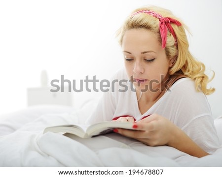 Happy blonde girl on bed in bedroom reading