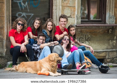 Young people sitting in group on the street smiling