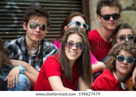 Cool teenage with sunglasses girl posing with friends on the street
