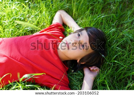 Little boy enjoying summer time lying on meadow green grass with sunbeam in his hair