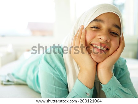 Beautiful Muslim girl lying down with hijab and smiling