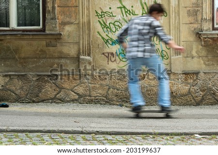 Boy riding a skateboard on a street in front of a graffiti wall
