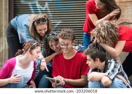 Smiling young people looking at a tablet computer on the street
