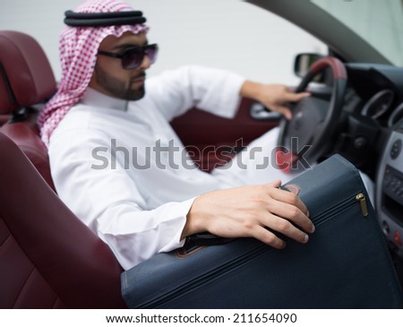 Arabic young businessman driving car and holding briefcase