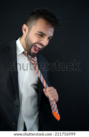 Portrait of attractive man pulling his tie and yelling