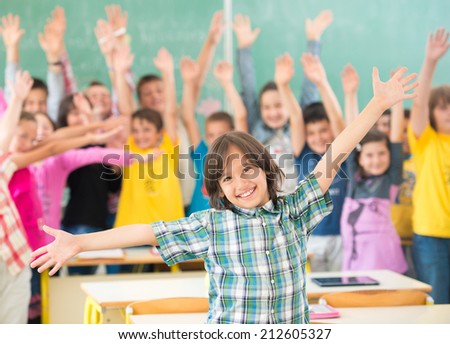 Group of kids having up rising hands with books in classroom