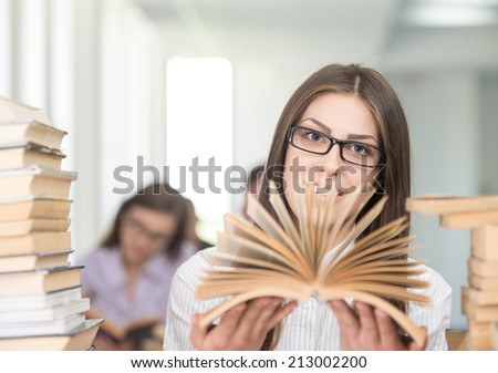 College girl student on university campus with open book in hands