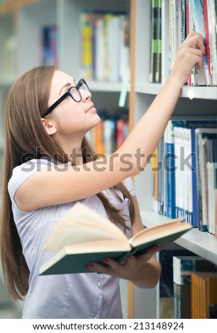 College student on university campus picking book from shelf