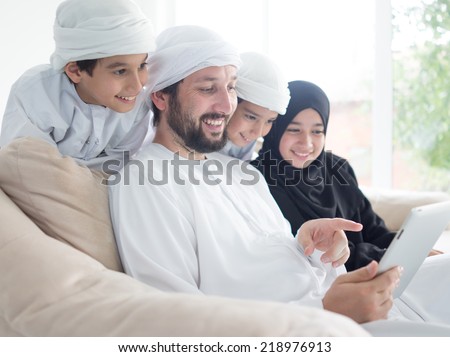 Middle eastern family at home on couch using tablet