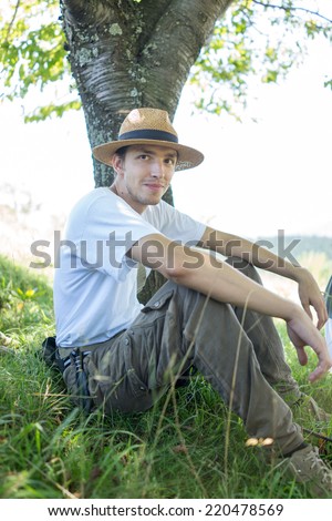 Young handsome man in nature sitting under the tree