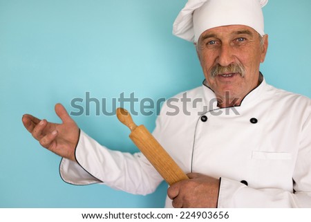Elderly chef in white cook uniform using rolling pin