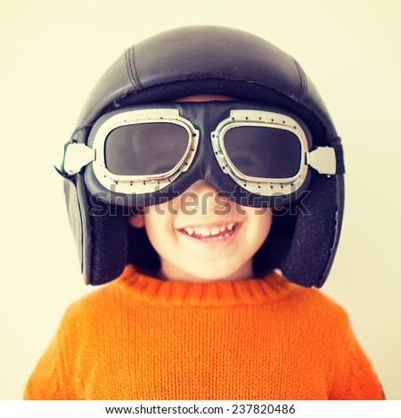 Little cute playful baby kid with pilot hat and goggles ready for airplane flying