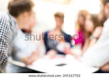 Image of business friends discussing brainstorming and ideas at meeting inside beautiful modern building place (Note: the image is out of focus, suitable as background)