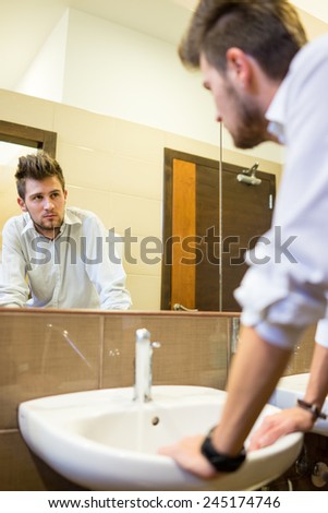 Young man washing face in bathroom