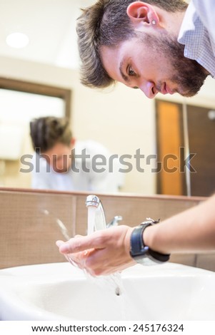 Young man washing face in bathroom