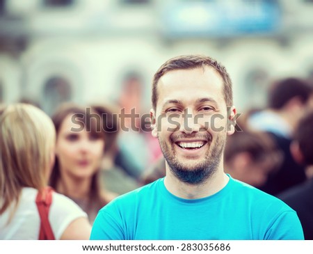Smiling man standing on a crowded street