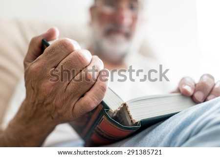 Elderly Arabic man sitting and reading book