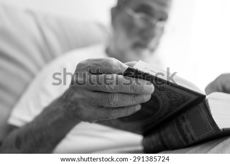Elderly Arabic man sitting and reading book