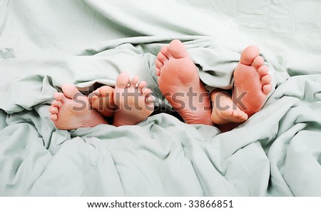 Tree pairs of legs of the happy family in bed - father, mother and son