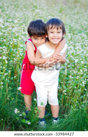 Two little brothers standing outdoor in grass