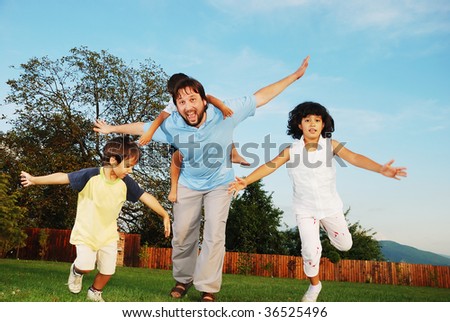 Happy family running outdoor, on beautiful garden