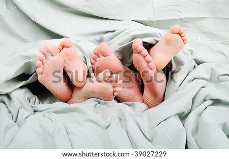 Happy family in bed under sheet