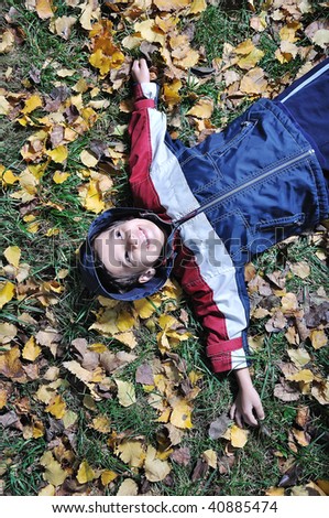 Little cute kid laying on the fall ground